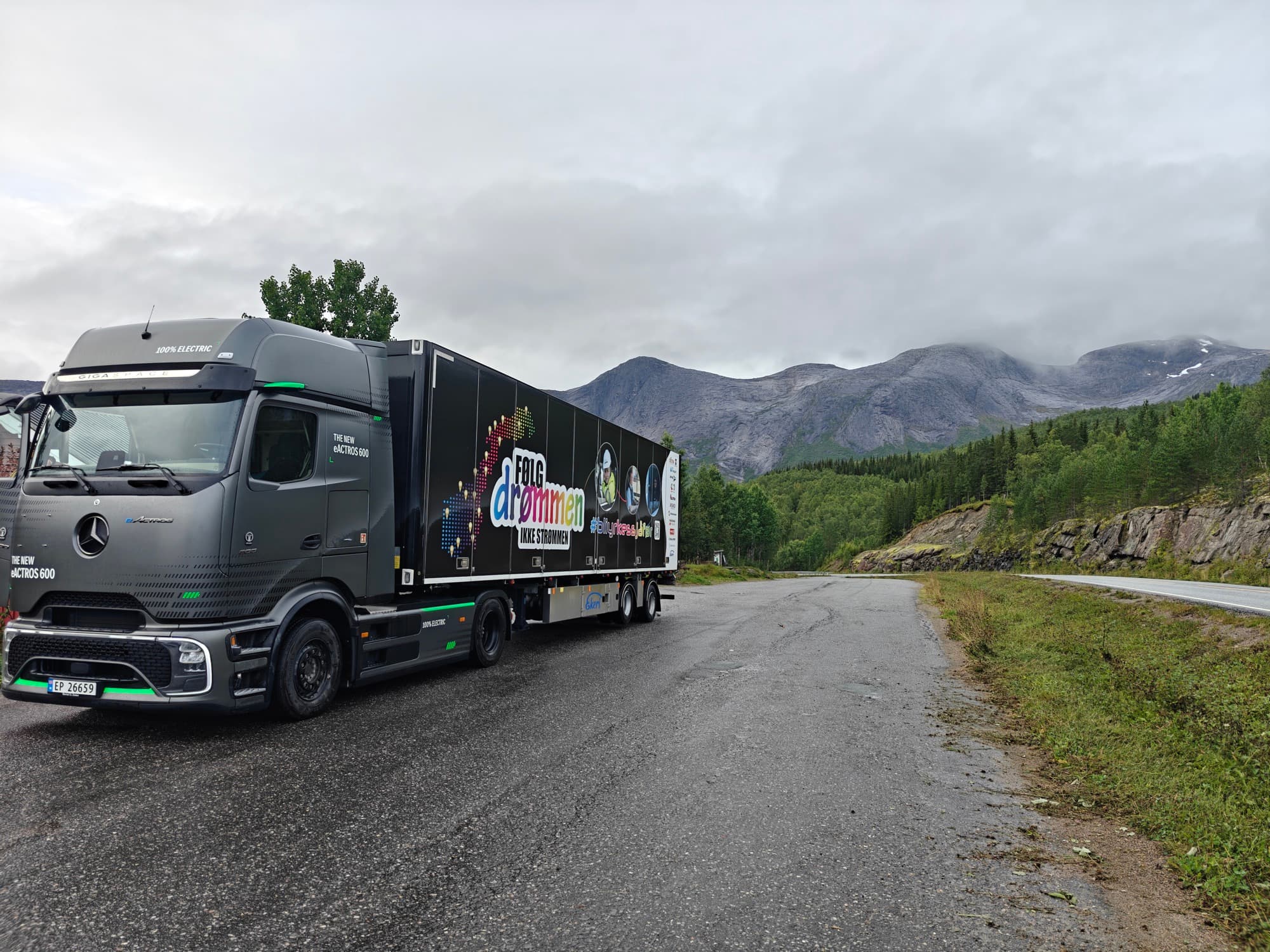Følg drømmen-turnébilen parkert ved veikanten med grønne fjell i bakgrunnen